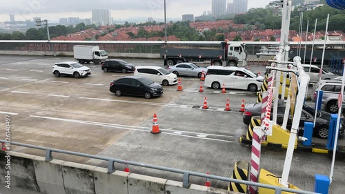 Heavy traffic in Malaysia queuing at a toll plaza. Drivers will make cashless toll payments using various accepted methods.