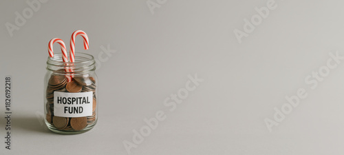 Candy cane jar filled with coins labeled hospital fund against gray background