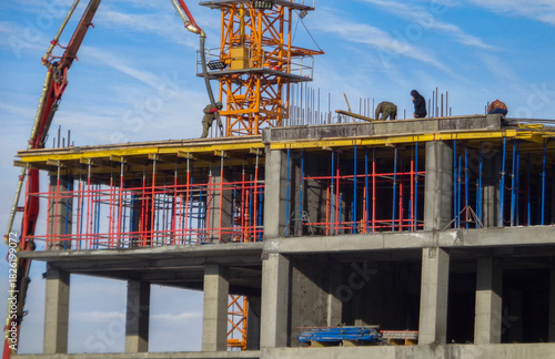 Apartment building under construction. Construction crane. Blue sky. Concrete frame. Workers. Floor pouring. Ust-Kamenogorsk (kazakhstan)