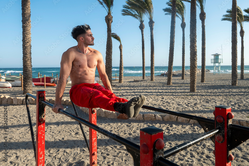 Fototapeta premium Man practicing l sit calisthenics on beach bars
