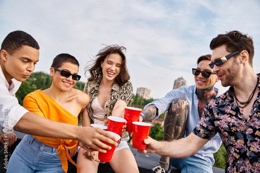 Fototapeta premium Young friends celebrate friendship and joy while partying on the roof under the bright sky