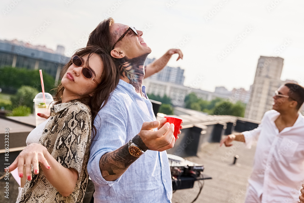 Fototapeta premium Young friends celebrate life together on a sunny rooftop with laughter and fun