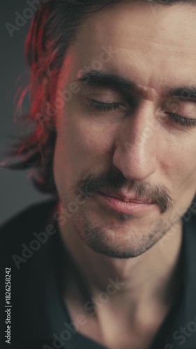 Sighing, Relieved, Exhaling, Nodding, Agreeing, Accepting Young Attractive Man with Long Hair and Mustache in Deep Expressions Against Dark Background – A Serene Exploration of Emotion