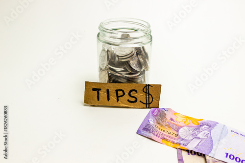 Tips money jar with coins and banknotes for service industry income
