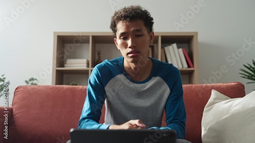 Asian teenage man learning sign language via internet with technology on tablet at home