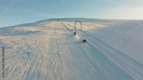 Bright snowy hillside, Golden glow over groomed slopes, Dawn illuminates snowy peak with active skiers, Sunshine highlights icy ridge and bustling winter recreation scene
