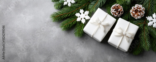 Christmas gifts with white wrapping and bows surrounded by pine branches, snowflakes, and pinecones on gray background