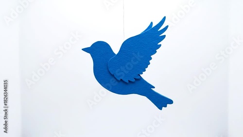 Blue Bird Silhouette Flying Against White Background.