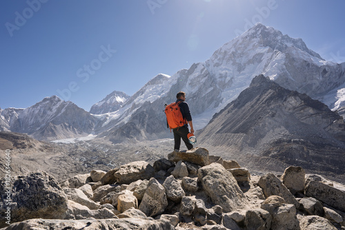 Hiker standing on rocky ridge facing Mount Nuptse, Everest Region, Nepal