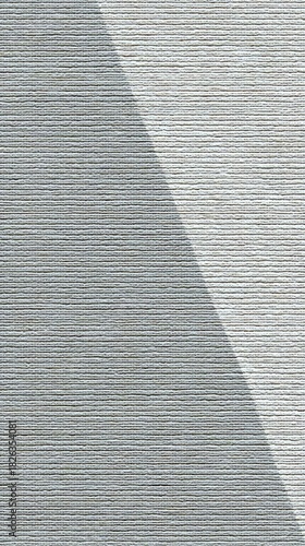 A close-up view of a textured gray surface divided by a diagonal shadow, creating a subtle contrast between light and dark areas.