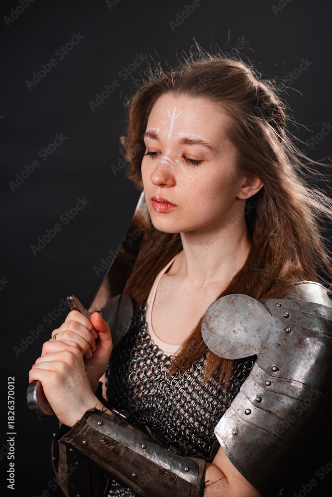 Obraz premium Portrait of a young woman, fantasy warrior in armor with a sword in her hands isolated on a dark background.