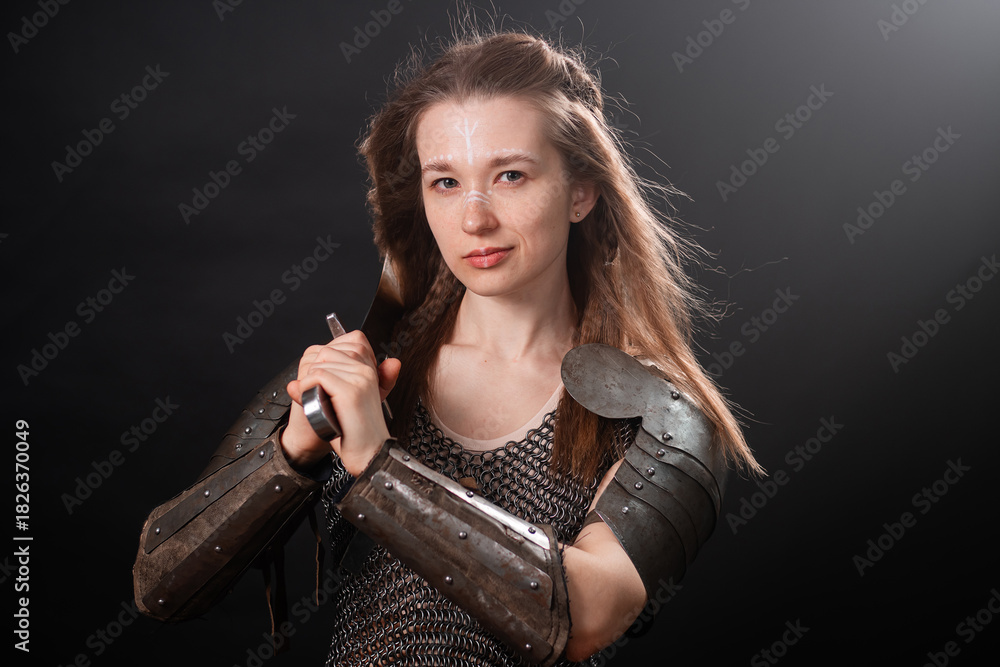 Obraz premium Portrait of a young woman, fantasy warrior in armor with a sword in her hands isolated on a dark background.