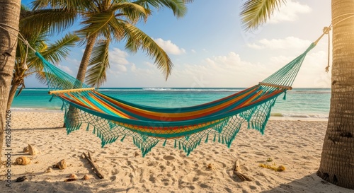 Fototapeta Naklejka Na Ścianę i Meble -  Hammock on sandy beach with palm trees and ocean in the background vacation concept