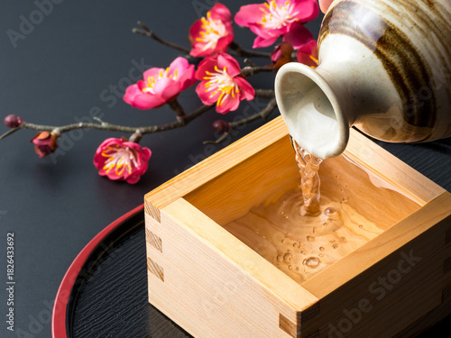 枡に注がれる日本酒と梅の花の静物