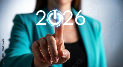Hand pressing a glowing 2026 power button, representing the start of a new year and future goals