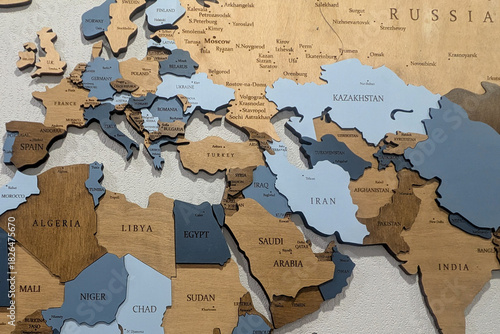 Detailed close-up of a wooden world map, showing countries in Europe, Middle East, and Asia with engraved city and country names.