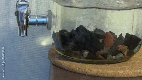 extreme close view fresh water pouring into glass carafe with mineral stones forming bubbles swirling around crystals natural filtration moment Concept of purification freshness and clean hydration