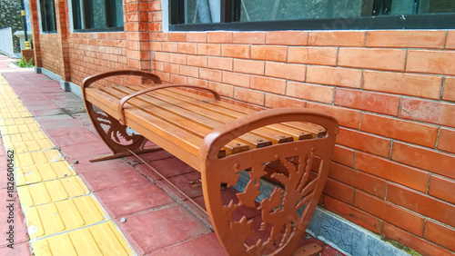 A wooden bench with a backdrop of a new exposed brick wall.