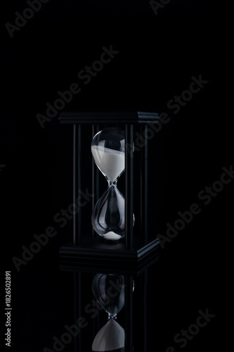Black Friday Urgency Symbolized by Hourglass, Sand Flowing in Glass Timer, Dark Dramatic Background Highlighting Last Minute Shopping Rush