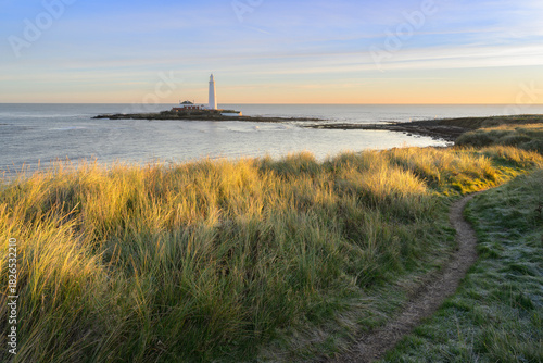 Peaceful footpath with view of St Mary's Island and Lighthouse on a beautiful sunny morning. Whitley Bay, North Tyneside, England, UK.