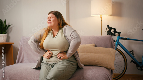 Obraz na plátne Overweight woman holds stomach bending forward in sudden pain