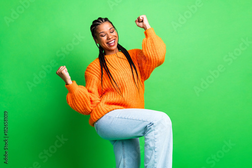 Tableau sur toile Young female model joyful moment celebration in orange knit sweater against brig