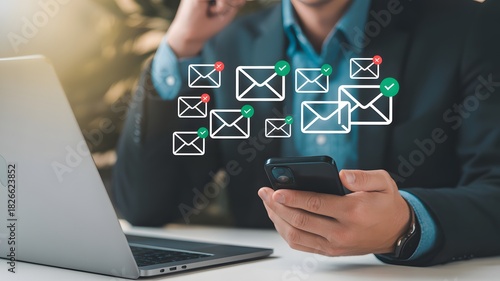 Businessman using smartphone and laptop surrounded by incoming email icons, digital communication marketing and message network concept