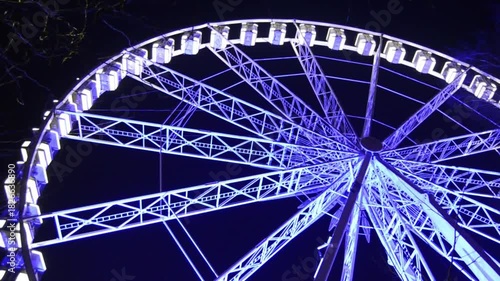 Low-angle view of a large Ferris wheel brightly illuminated against the night sky.