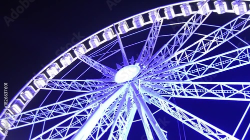 Low-angle view of a large Ferris wheel brightly illuminated against the night sky.