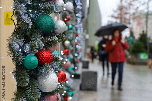 New Year decorations in rainy city, Christmas balls on a street on blurred background of people