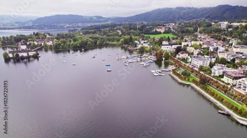 Drone approach to Gmunden yacht harbor with autumn park and coastline
