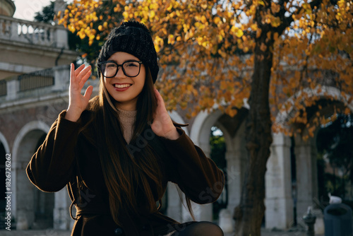 Mujer joven probándose o ajustándose gafas de ver en un parque urbano.