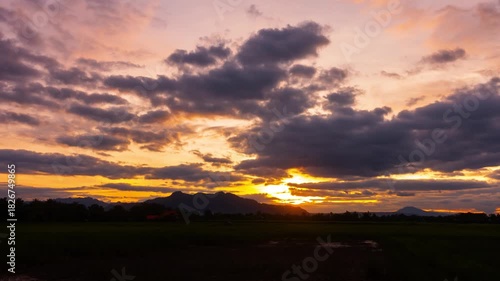 Sunset with the sun in the clouds behind the mountains in the distance with time remaining