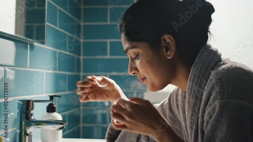 Woman Applying Contact Lenses in Bathroom Vanity with Blue Tiled Wall and Soft Natural Light