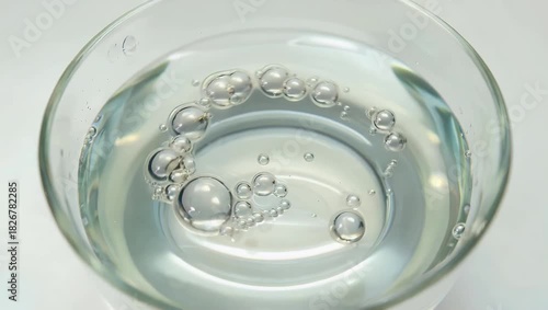Scientific 4K Ultra HD laboratory video showing a clear liquid with gently swirling bubbles against a clean white background illustrating chemistry science laboratory work and the important research