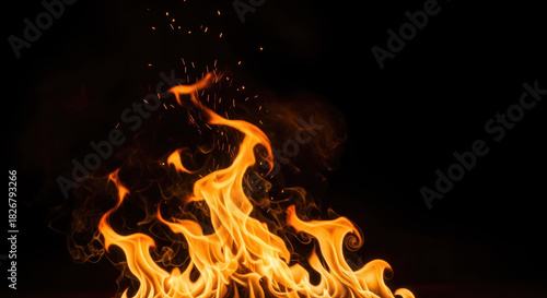 Vibrant and intense orange flames flicker dynamically, casting a warm glow against a dark black background with ample copy space for text.