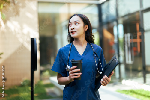 Asian healthcare worker walking with coffee and folder