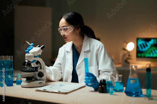 Photos Female scientist performing medical research in a dark laboratory
