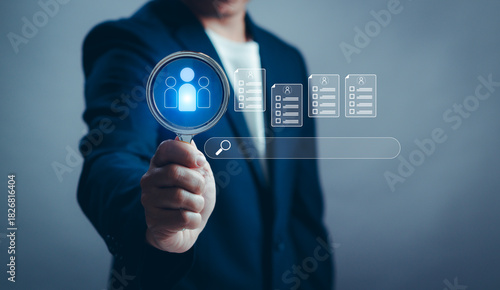 Businessman holding magnifying glass with people icon showing search and evaluation of candidate profile, HR technology recruitment concept, talent selection and digital human resource management