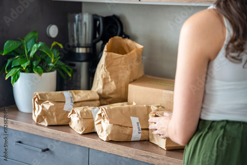 A set of brown paper packages labeled on a kitchen counter. Meal kit delivery with pre-portioned ingredients sorted by recipe for convenient home cooking.
