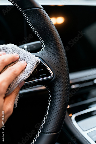 Car detailing service focuses on cleaning steering wheel with microfiber cloth in a modern automotive setting