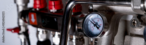 Complex residential heating manifold system with valves, gauges, and piping network. banner