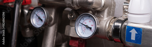 Complex residential heating manifold system with valves, gauges, and piping network. banner