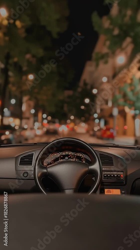 Car interior view at night showing dashboard and steering wheel while distant street lights shift slightly as the vehicle moves forward creating a calm urban driving scene