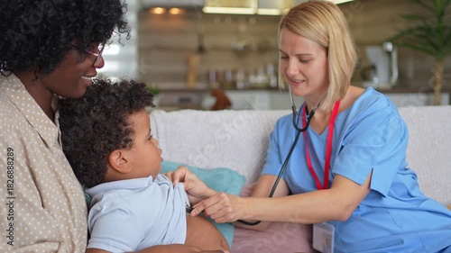 Female pediatrician examining a mixed-race boy on a sofa