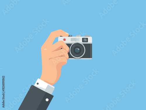 Wektorowa ilustracja dłoni trzymającej klasyczny aparat fotograficzny retro, idealna do uchwytywania chwil i dokumentowania wspomnień na jasnoniebieskim tle.