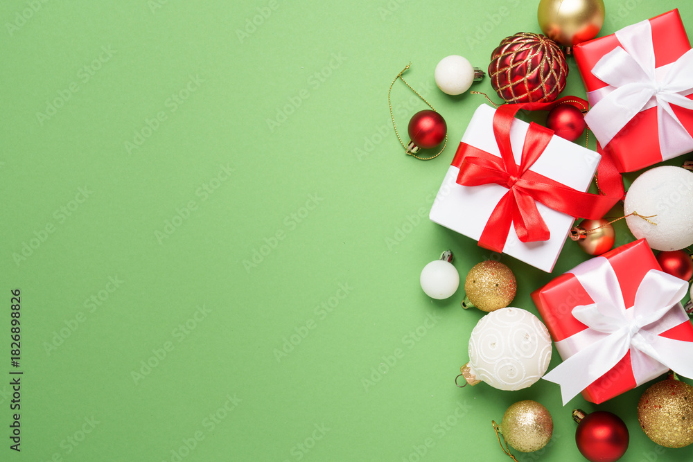 Obraz premium Christmas gift box and holiday decorations at green background.