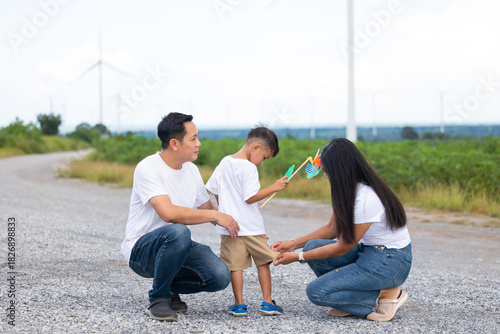 Asian family in field with wind turbines in the background, Windmill. environmental renewable clean energy. Wind power generation