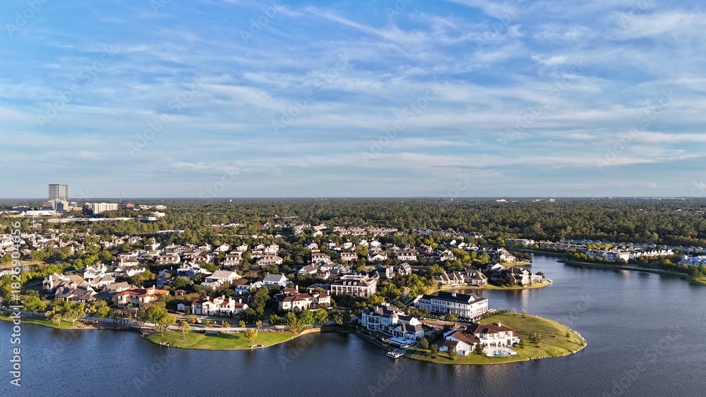 Obraz premium Aerial view of large mansion houses with swimming pool, in affluent neighborhood by Woodlands lake, Houston, Texas, expensive suburban homes surrounding by lush green trees, USA