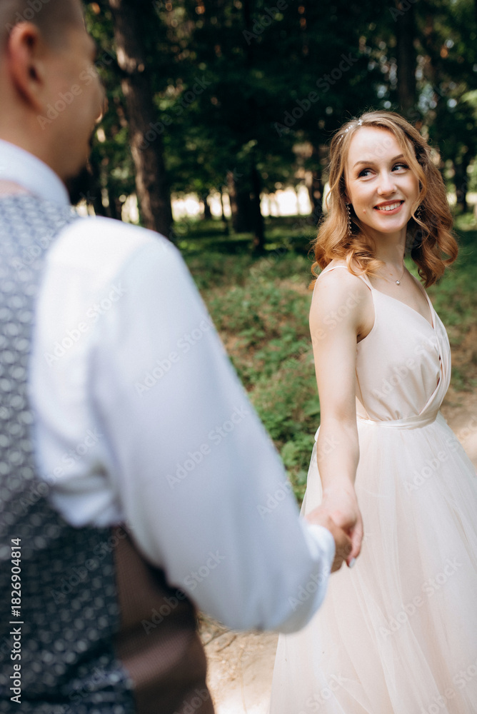 Naklejka premium the bride and groom are walking in the park along the paths